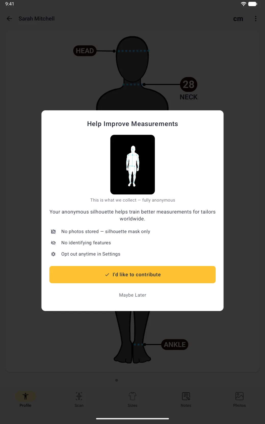 A wide white dialog over the dimmed Sarah Mitchell profile titled Help Improve Measurements, with a white body outline and cyan pose points on a black panel, the caption This is what we collect, fully anonymous, the line Your anonymous silhouette helps train better measurements for tailors worldwide, three grey-icon points reading No photos stored, silhouette mask only, No identifying features and Opt out anytime in Settings, a gold I'd like to contribute button with a tick and a grey Maybe Later link.