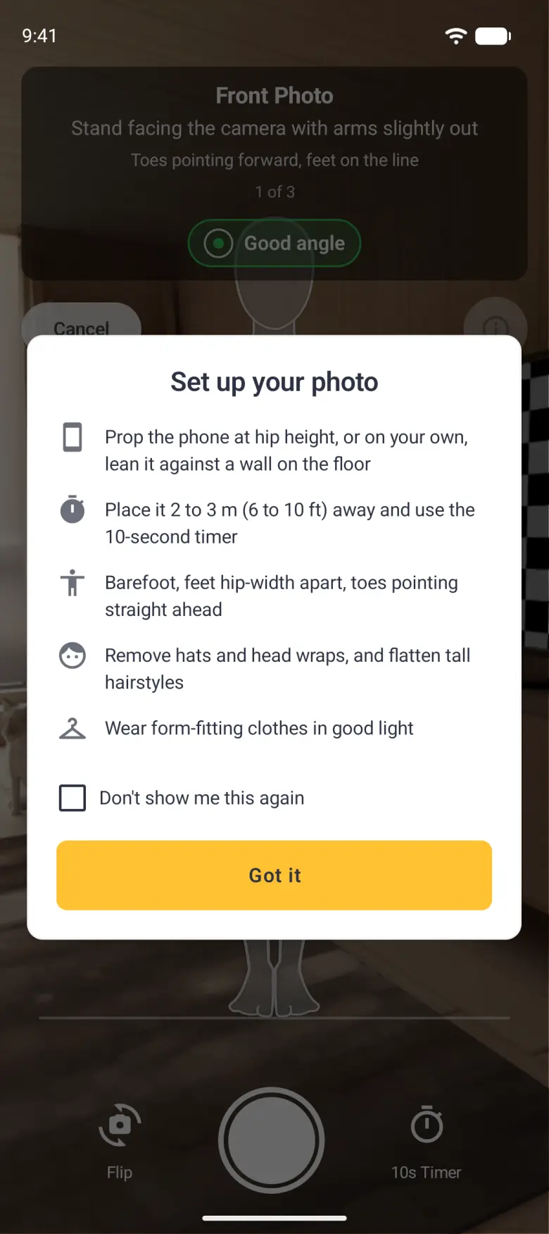 A Set up your photo card over the dimmed camera screen, below the Front Photo banner with its green Good angle pill and the Cancel and i buttons, with five tips each beside an icon (prop the phone at hip height or on your own lean it against a wall on the floor, place it 2 to 3 m (6 to 10 ft) away and use the 10-second timer, barefoot with feet hip-width apart and toes pointing straight ahead, remove hats and head wraps and flatten tall hairstyles, wear form-fitting clothes in good light), an unticked Don't show me this again checkbox and a gold Got it button, with Flip, the shutter and 10s Timer dimmed along the bottom.