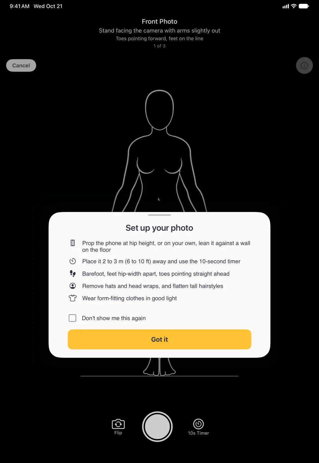 A Set up your photo card centred over the full-screen black camera screen in portrait, which keeps its Front Photo banner (Stand facing the camera with arms slightly out, Toes pointing forward, feet on the line, 1 of 3), a Cancel button at the top left, the info button at the top right, the white line-art body guide above a floor line and Flip, shutter and 10s Timer controls at the bottom; the card has a grabber, five tips each led by an icon (prop the phone at hip height or, on your own, lean it against a wall on the floor; place it 2 to 3 m, 6 to 10 ft, away and use the 10-second timer; barefoot, feet hip-width apart, toes pointing straight ahead; remove hats and head wraps and flatten tall hairstyles; wear form-fitting clothes in good light), an unticked Don't show me this again checkbox and a gold Got it button.