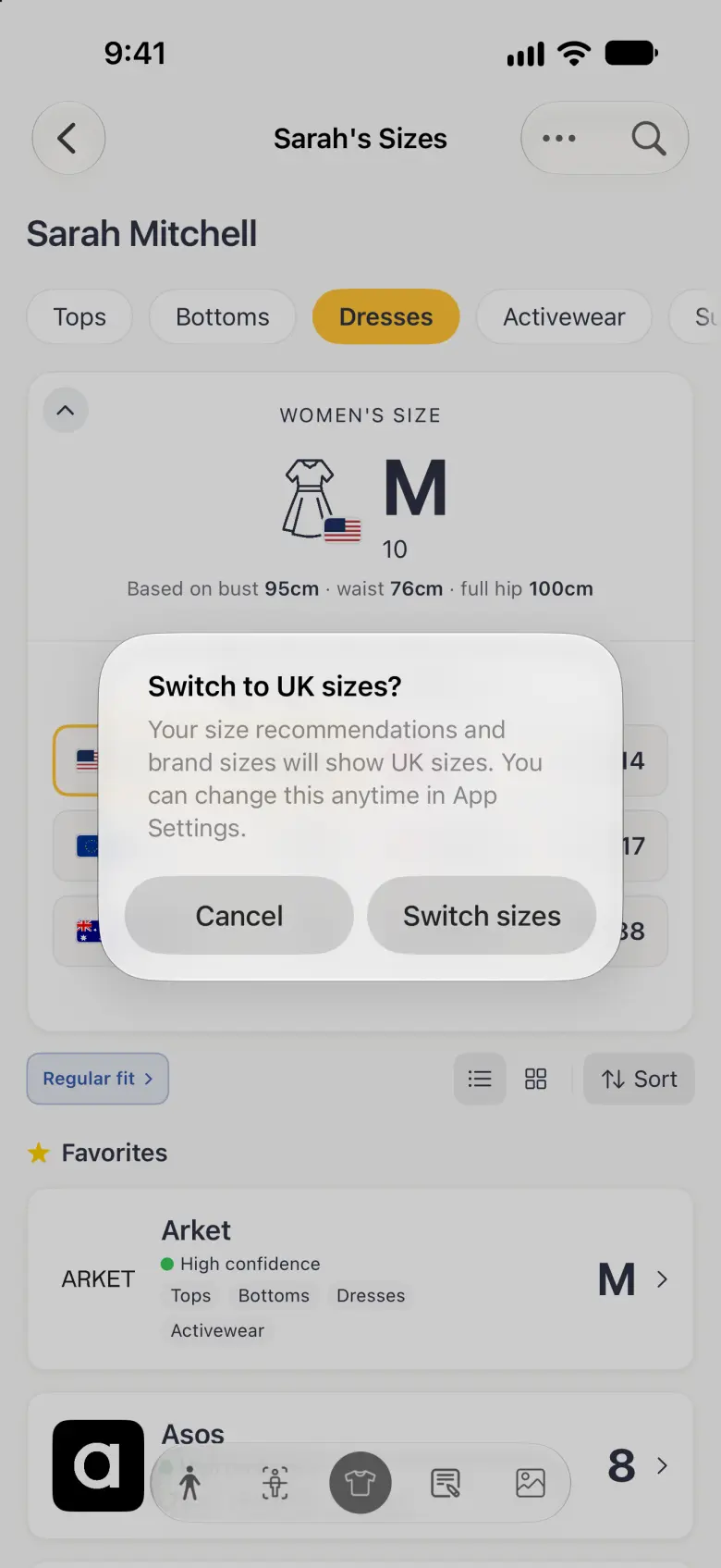 A system alert over the dimmed Sizes screen titled Switch to UK sizes? explaining that size recommendations and brand sizes will show UK sizes and can be changed in App Settings, with Cancel and Switch sizes buttons side by side.