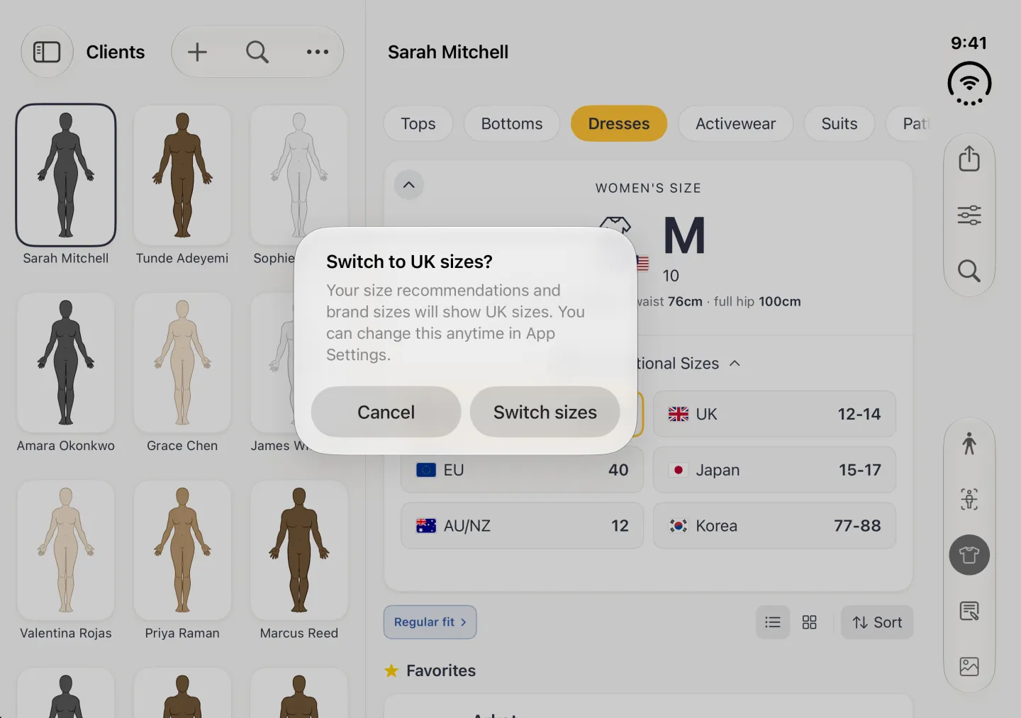 A system alert near the UK tile over the dimmed split view, titled Switch to UK sizes? explaining that size recommendations and brand sizes will show UK sizes and can be changed in App Settings, with Cancel and Switch sizes buttons side by side.