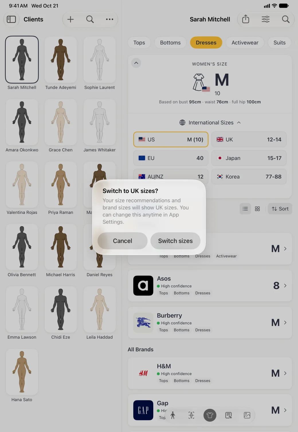 A system alert centred on the dimmed split view of the Clients grid and the Sizes section, titled Switch to UK sizes? and explaining that size recommendations and brand sizes will show UK sizes and can be changed anytime in App Settings, with Cancel and Switch sizes buttons side by side.