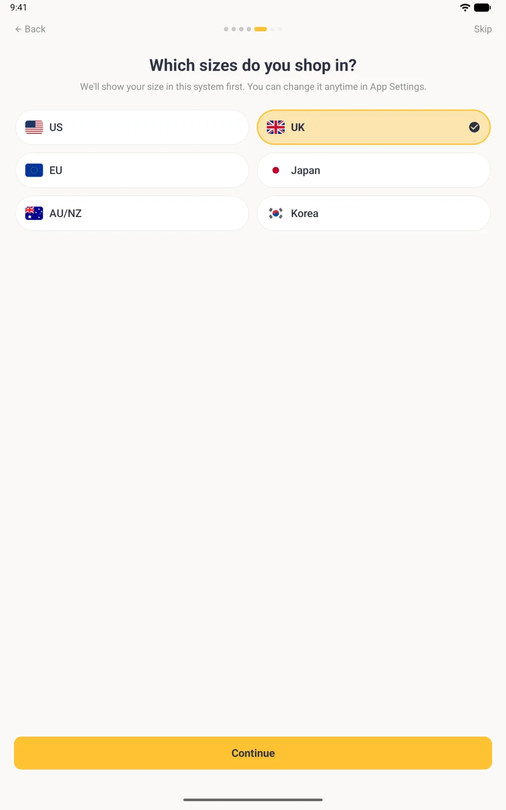 Which sizes do you shop in? step under seven page dots, the fifth one active, with the line We'll show your size in this system first. You can change it anytime in App Settings, six wide pill buttons in two columns for US, UK, EU, Japan, AU/NZ and Korea, each with its flag, UK filled pale gold with a gold border and a navy tick, above a gold Continue button.