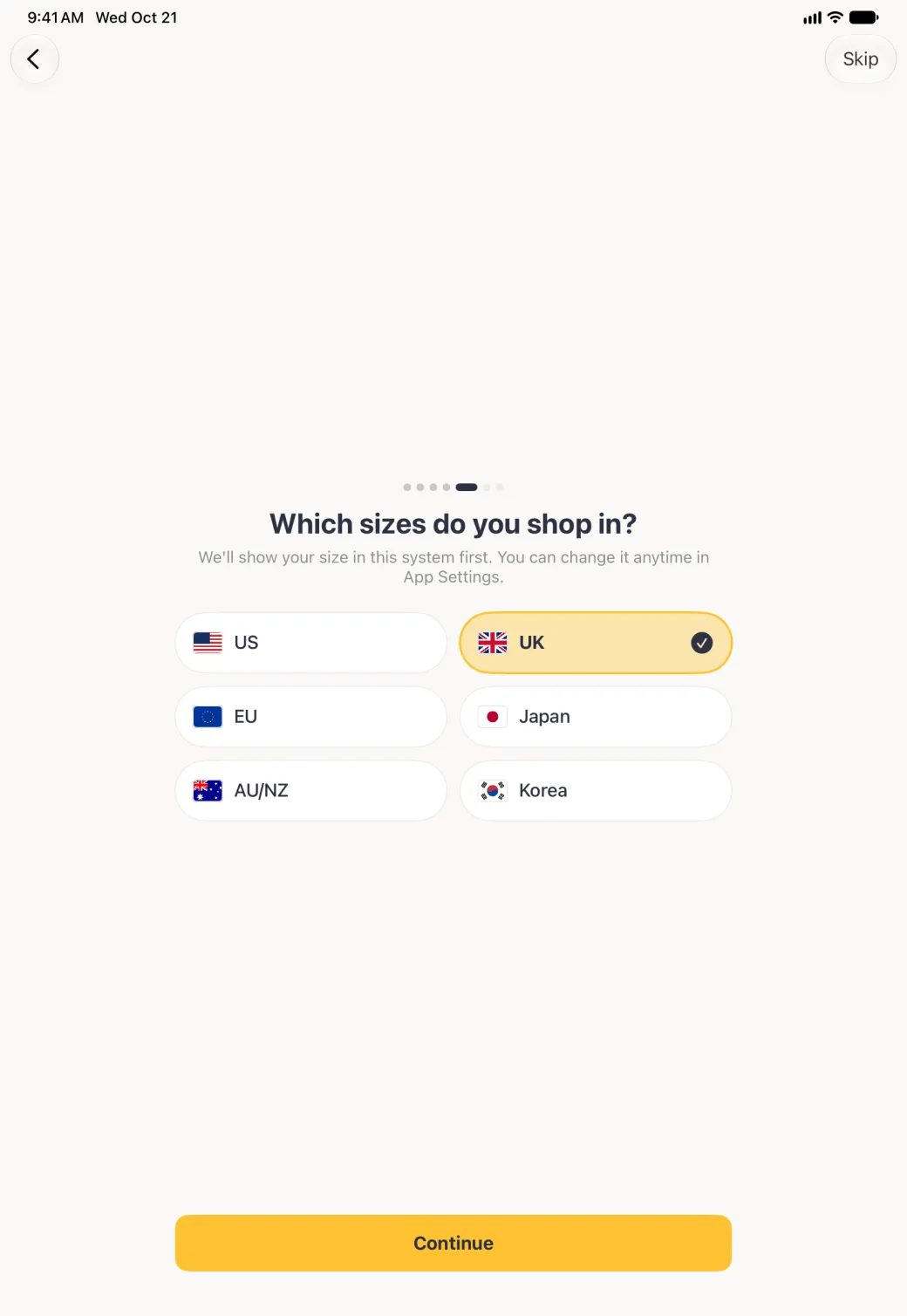 Which sizes do you shop in? step in portrait with the fifth of seven page dots filled and six wide region buttons in two columns centred on the screen, US, UK, EU, Japan, AU/NZ and Korea, each with its flag, UK highlighted in gold with a navy tick, above a gold Continue button; Back sits at the top left and Skip at the top right.