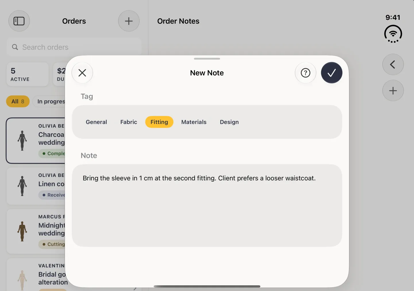 New Note sheet in landscape with the Fitting tag selected, a note reading Bring the sleeve in 1 cm at the second fitting. Client prefers a looser waistcoat., and the round tick at the top right now solid navy; no keyboard on screen.
