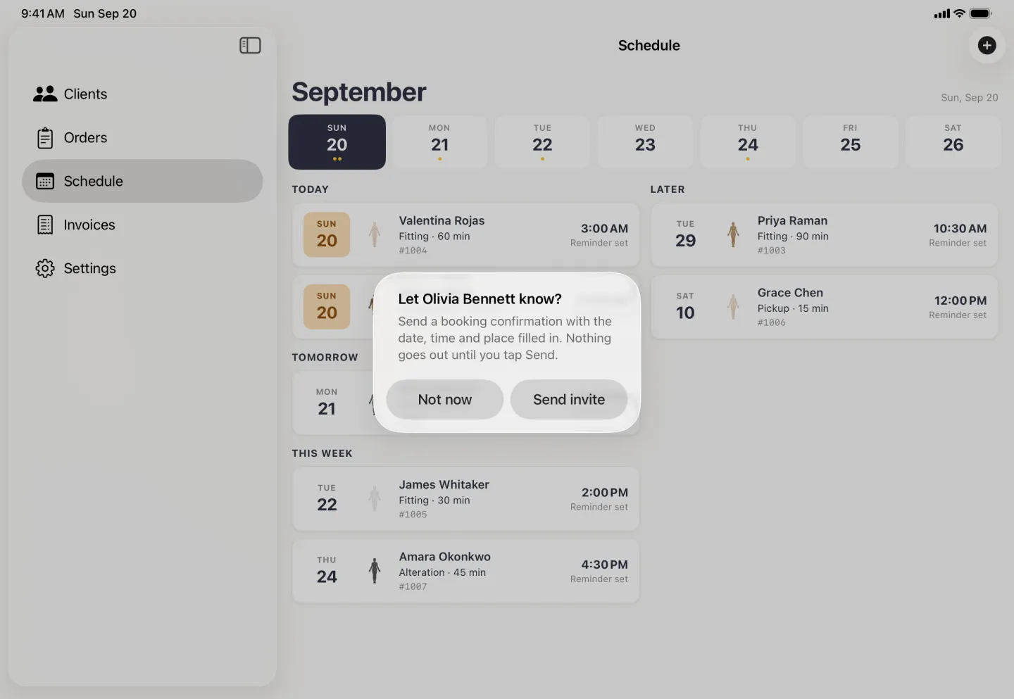 Alert centred over the dimmed Schedule pane and sidebar reading Let Olivia Bennett know? with the line send a booking confirmation with the date, time and place filled in, nothing goes out until you tap Send, and Not now and Send invite side by side. A Tomorrow group has appeared in the schedule behind it.