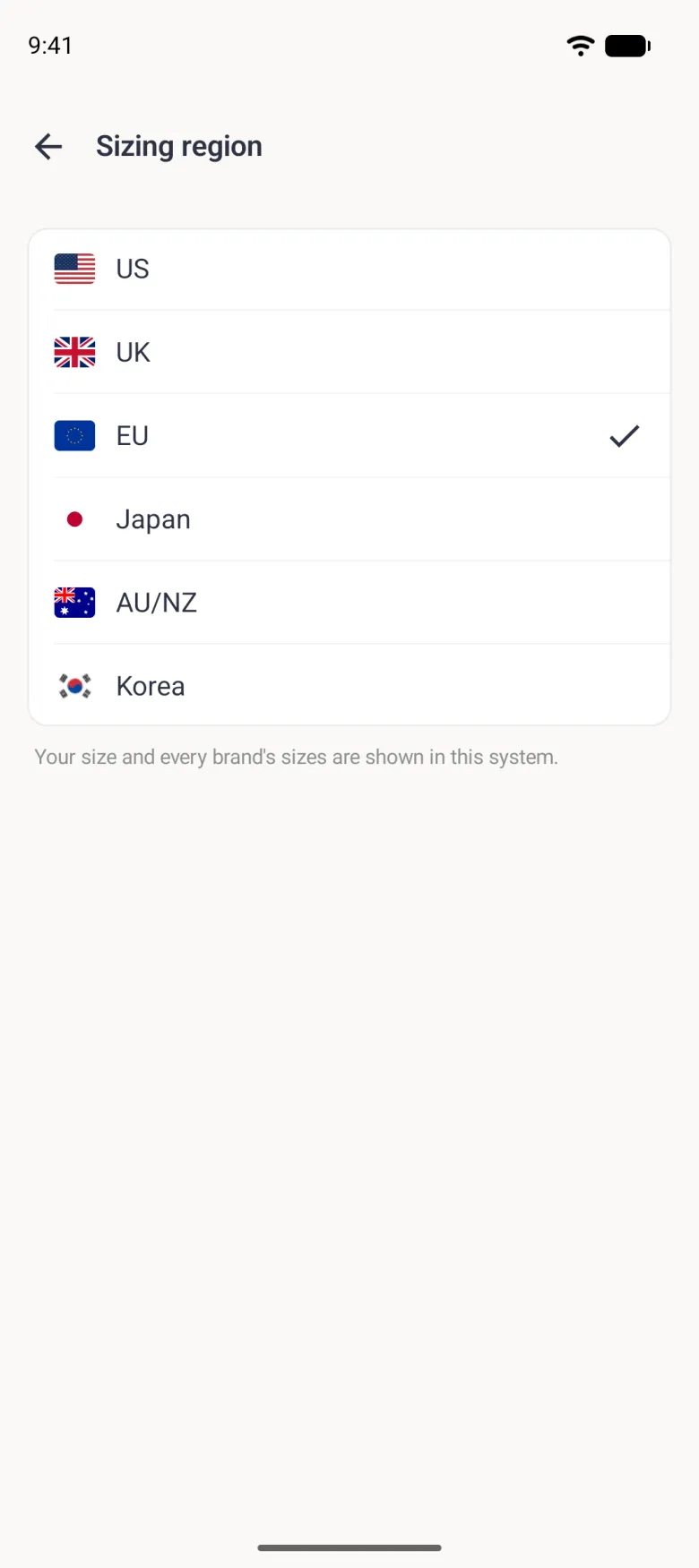 Sizing region screen with a back arrow and a white card of six rows, US, UK, EU, Japan, AU/NZ and Korea, each with its flag, EU with a navy tick at the right, above the note Your size and every brand's sizes are shown in this system.